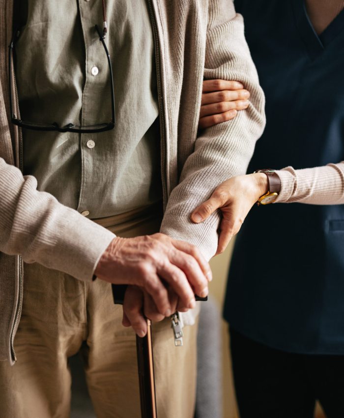 An anonymous Japanese female caregiver supporting elderly patient to stand and walk with a walking cane at the nursing home.